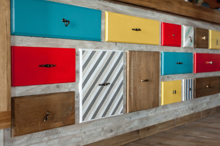 Colorful decorative drawers with handles are attached to the wall. Multicolored wooden decorative elements. Interior design in a cafeの写真素材