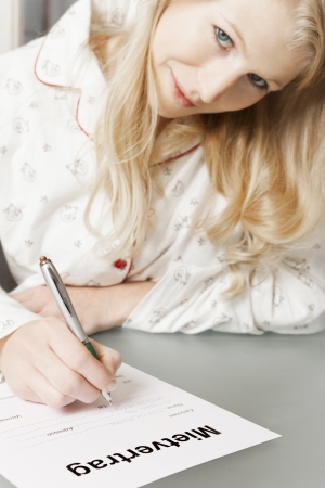 Woman in pajamas completes rental agreementの写真素材