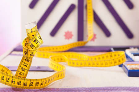Yellow measuring tape meanders out from a sewing box