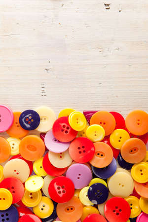 A pile of colorful buttons with copy space on woodの写真素材