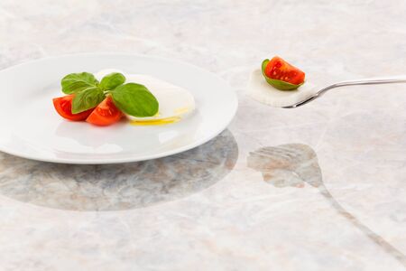 Mozzarella salad with tomatoes and basil on a fork
