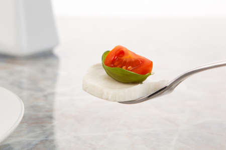 Mozzarella salad with tomatoes and basil on a fork