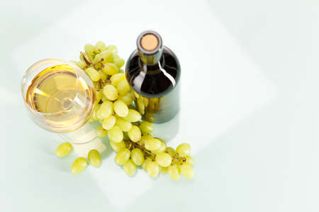 White wine in glass and bottle with bunch of grapesの写真素材