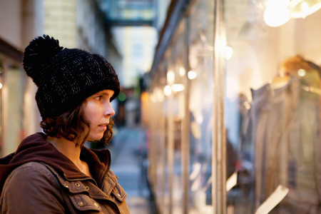 Woman with thoughtful look to the shop window