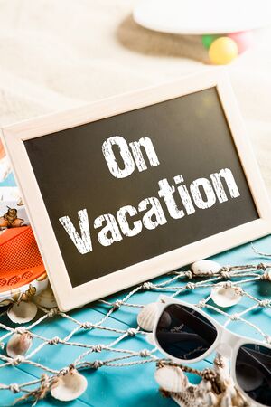 Beach with holiday gear and a board with the words On Vacationの写真素材