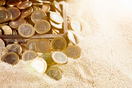 Euro coins on a sunny sandy beachの写真素材