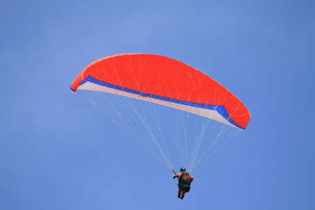 Single paraglider with red glider in a blue skyの写真素材