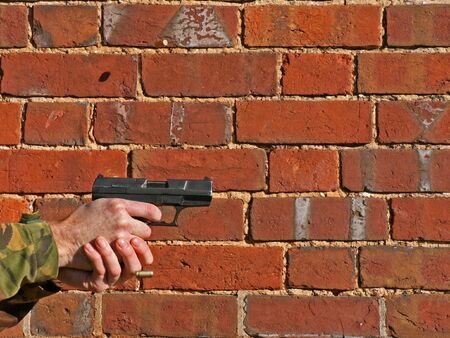 A 9mm Pistol being fired with two ejected cases in the air this is against a brick wall
with just the hand and some sleeve showing with room for textの写真素材