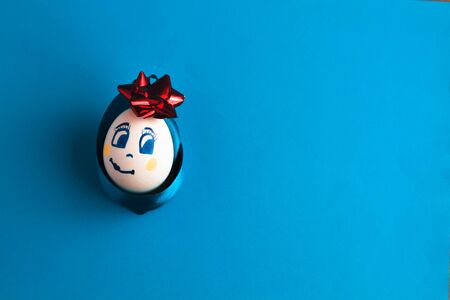 festive egg with bow and smile, on blue background .close up, top view.の写真素材
