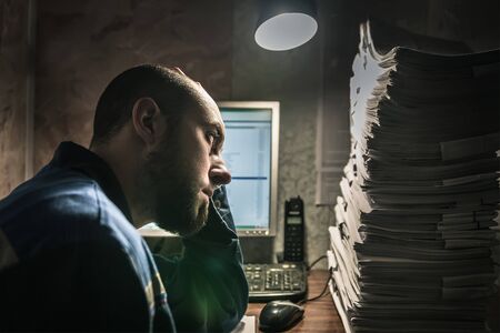 a young man in a overalls looks tired look at the upcoming work.の写真素材