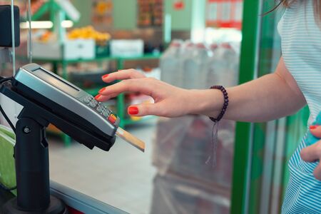 Woman pays for purchases in the store by credit card through the payment terminal.の写真素材