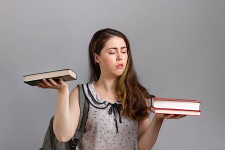 Education. A young woman or teenager with a backpack on her back, holding books in her hands, and...