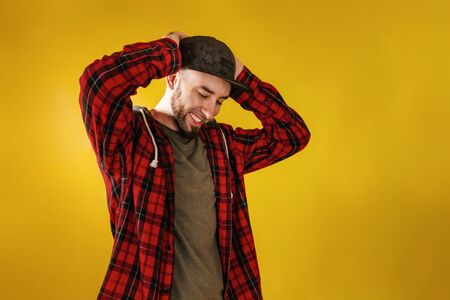 Concept People and emotions. A man in a black cap and red plaid shirt, happily holding his head....