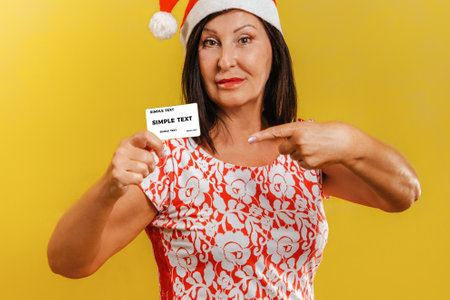 New year and shopping. A woman in a Christmas hat, holding a Bank card. Yellow background and snow....