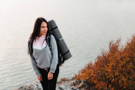 The concept of Hiking and sports recreation. Beautiful young woman with a tourist backpack behind...