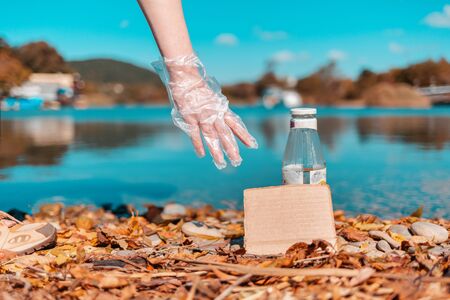Protection of the environment and Earth Day. A female volunteer picks up a glass bottle, near which...