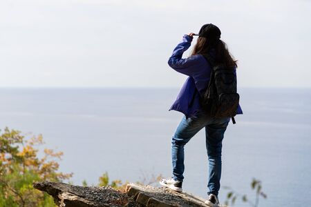 Sports and tourism. A woman with a backpack on her back looks into the distance. In the background,...