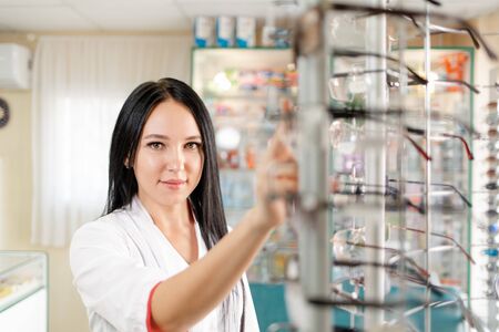 Medicine, pharmacy and optics. Portrait of a woman doctor or pharmacist in a white coat and pulling...