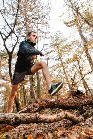 The concept of sports and cross-country running. A man in sports clothes jumps branches on the...
