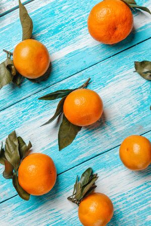 Tangerines with leaves lie on a wooden blue table. Strips of boards on the diagonal. Vertical orientation. Close up.の写真素材