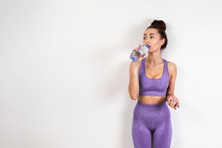 The concept of healthy eating. A young white woman in lilac sportswear, with a toned figure,...