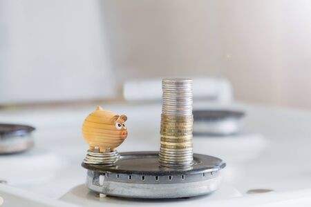 the concept of saving money.toy little pig about a stack of coins that are on the burner gas.