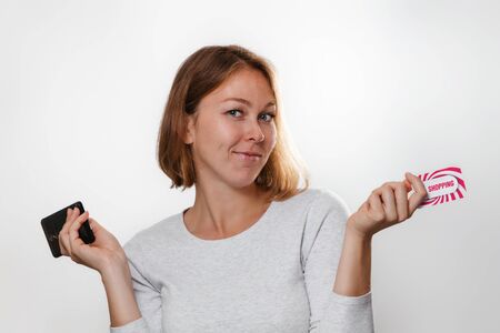 Shopping and Finance. A beautiful young woman with a smile holding a mobile phone and a Bank card. White background.の写真素材