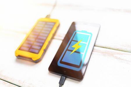 Concept of modern technologies and power bank. Smartphone with a blue battery icon, charged from a...