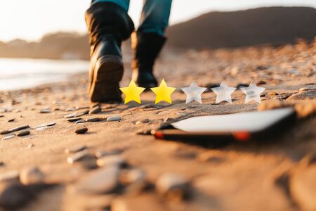The concept of smartphone apps. The smartphone lies on the sand, on the beach. In the background, blurred removing footsteps of a man. Rated 2 out of 5 stars.の写真素材