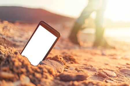 The concept of the photos on the phone. The smartphone lies buried in the sand on the beach, and...