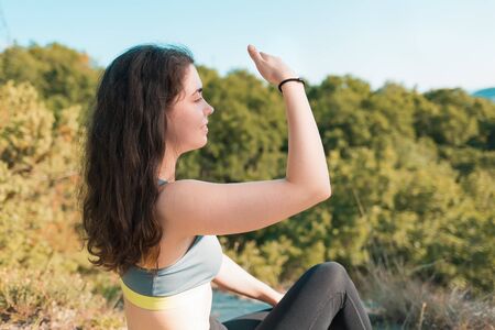 Young athletic woman sitting resting and looking into the distance. Forest in the background....