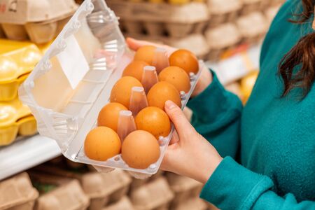 A woman holds an open package of chicken eggs. Hands and balls close-up. The concept of buying organic products.の写真素材