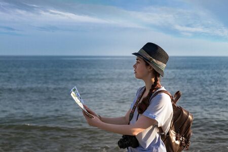 the girl with the camera, backpack and hat looking at the map.