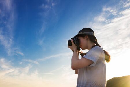 girl photographer takes a picture against the blue sky and sunset, the bottom view.