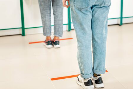 People stand in line, legs close-up. Attention line on the floor of the store to maintain social...