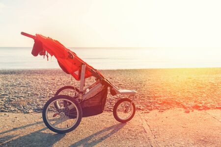 Baby stroller on the background of the sea and deserted beach on a Sunny day. Nobody. Copy space.