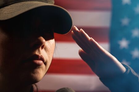 Memorial day. A female soldier in uniform salutes against the background of the American flag....