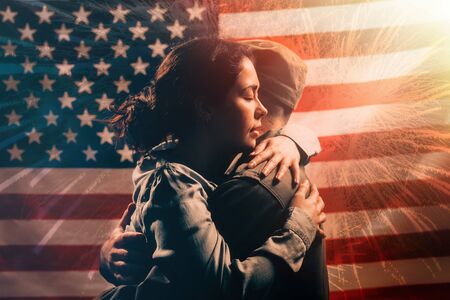 Veterans Day, Memorial Day. A woman embraces a soldier. Couple on the background of the American flag with fireworks. The concept of the American national holidays and patriotism.の写真素材