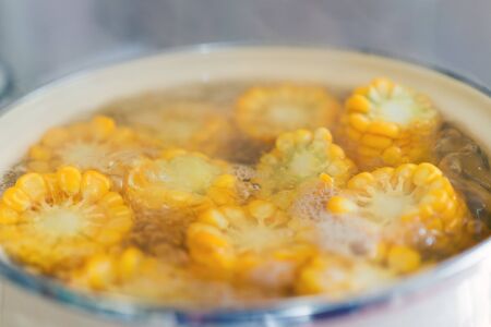 the process of making sweet corn in a pot on the gas stove at home.