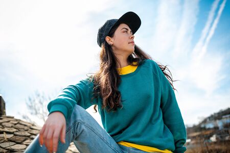 A young pretty woman in casual clothing poses against a blue sky. Copy space. Concept of new ideas, reflections and advertising.の写真素材