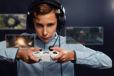 The concept of video games. A teenage boy, in headphones with a serious look playing a game. In the...