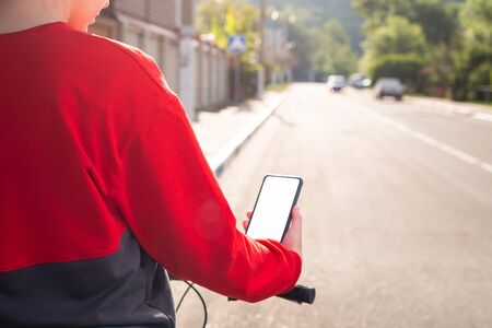 A woman holds a smartphone with an online map app. Rear view. In the background is a city street. Mock up. Close up and rear view. The concept of Internet navigation and modern technologies.の写真素材