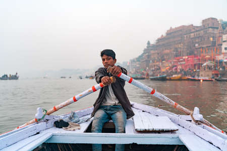 16.12.2019 Varanasi, India. Portrait of an Indian male boatman who paddles while transporting a...