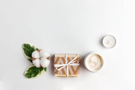 Cosmetics and self-care. A cotton flower with green leaves, handmade soap, a jar of cream and a...