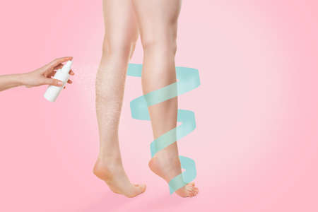 A woman stands on her toes, and a cosmetic or medicinal product is sprayed on her shins. Copy space. A blue ribbon curls around the leg. Pink background. The concept of health, freshness and beauty of the legs.の写真素材