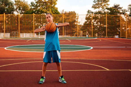 Basketball A teenage boy in green sportswear plays a basketball. In the background is a sports...