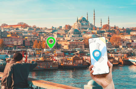 A hand holds a smartphone with an online maps app. In the background, a view of Istanbul, the Bayの写真素材