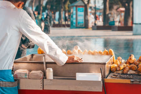 Traditional street food. The corn seller stands behind the counter with a cigarette in his hands. Rear view. Close up.の写真素材