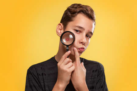 Cosmetology, Dermatology and acne. A teenage boy in a black t-shirt with pimples on his face,...
