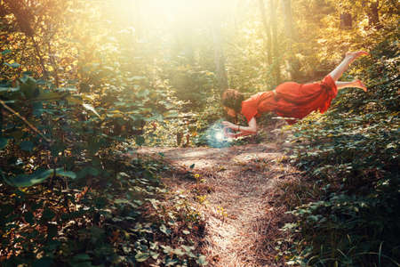 Fantasy. A young brunette woman in the form of an elf, druid, or fairy hovering over an energy ball....